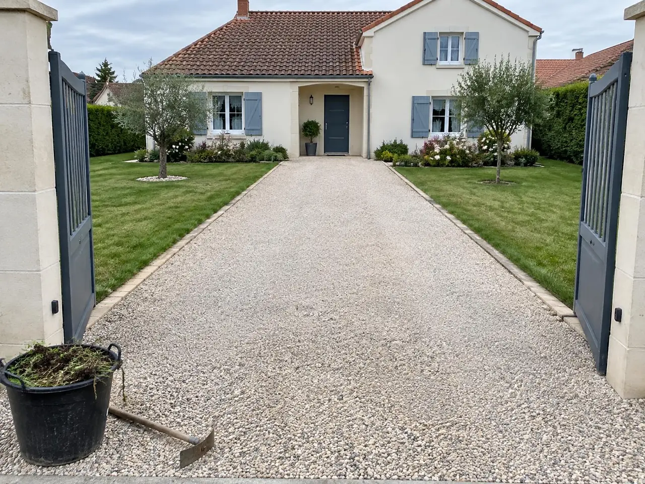 La même allée désherbée et ratissée, pelouses tondues et bordées, seau d'herbes arrachées et binette à l'entrée
